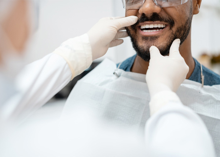 Man smiling, having his teeth examined by a dentist.