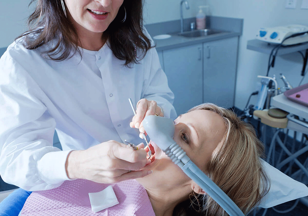 Dentist providing laughing gas while working on a patient.